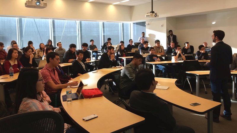 Students and faculty seated in a tiered classroom at the Club&rsquo;s kickoff meeting, with a speaker standing at the right